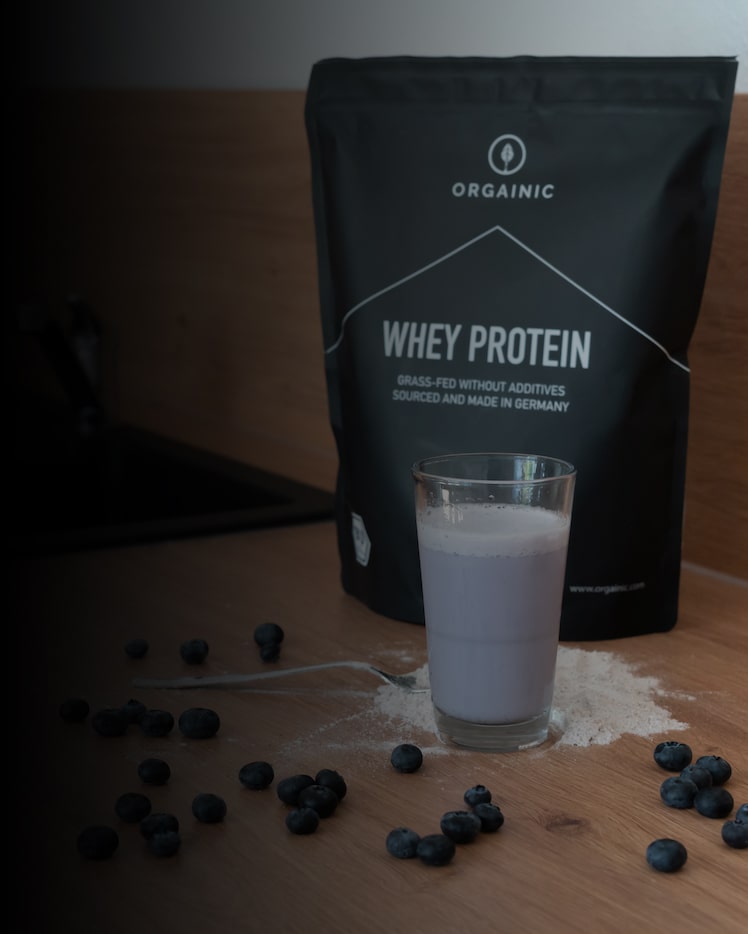 ORGAINIC Whey Proteinpulver am Tisch mit Glas